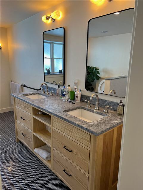 Double-sink custom wood vanity with a stone top and framed mirrors