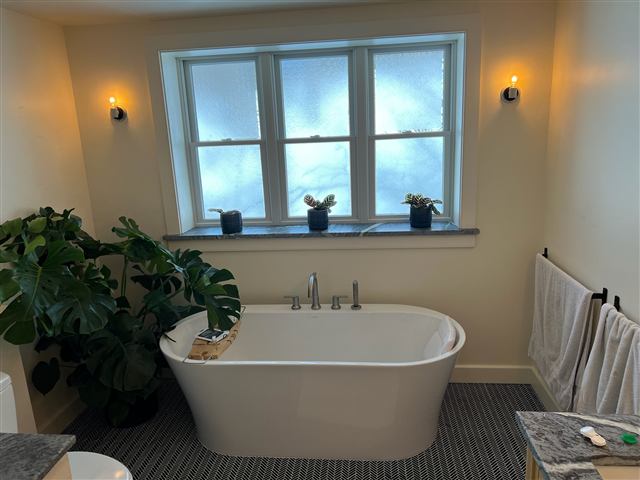Bathroom with a freestanding tub beneath a large window