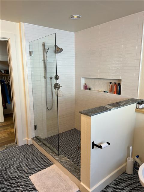 Glass-enclosed walk-in shower with white subway tile and a built-in niche