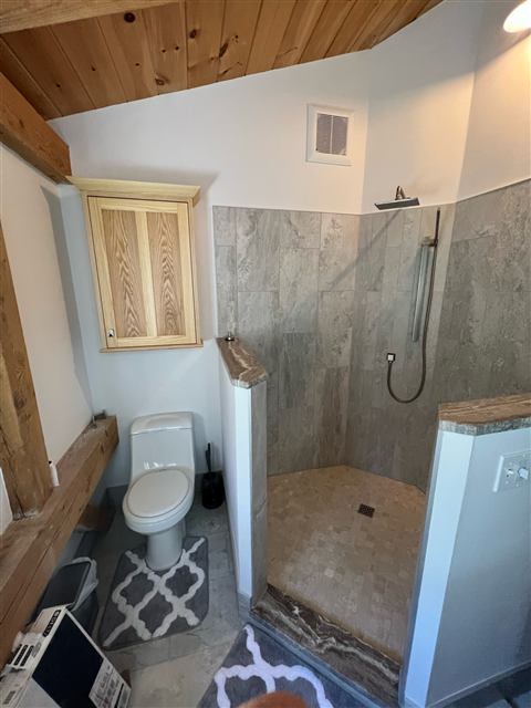 Bathroom with a stone-look walk-in shower and exposed timber