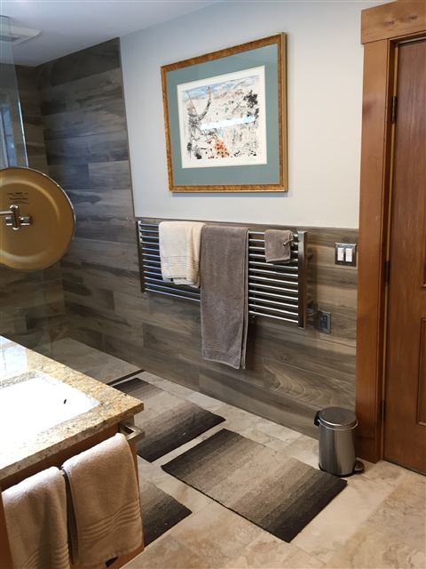 Bathroom wall of wood-look tile with a heated towel rail