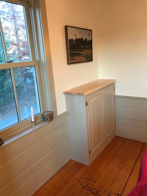 Painted built-in cabinet with a wood top and shiplap wainscot