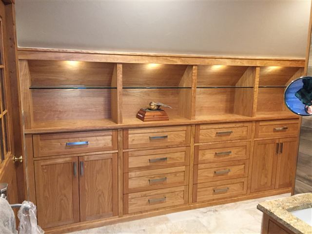 Built-in cabinetry with lit open shelves and a bank of drawers
