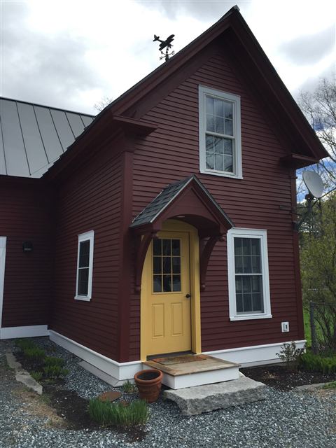 Red clapboard addition with a yellow entry door