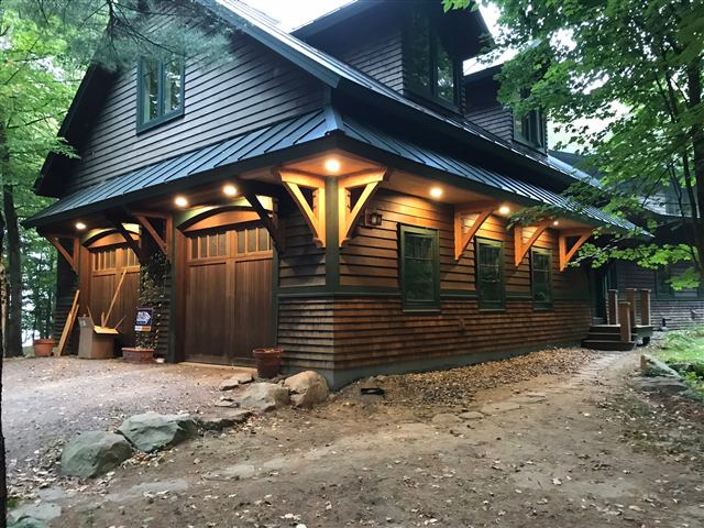 Timber-accented garage with bracketed eaves and lighting
