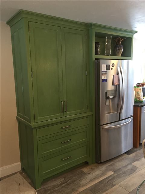 Painted green tall cabinet built around a refrigerator