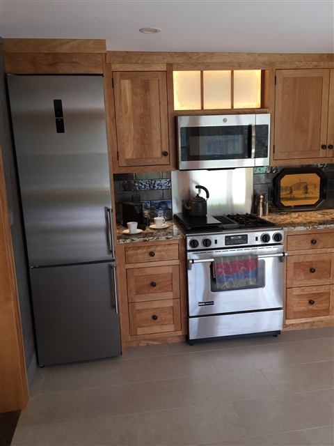 Kitchen cabinetry framing a stainless refrigerator and range