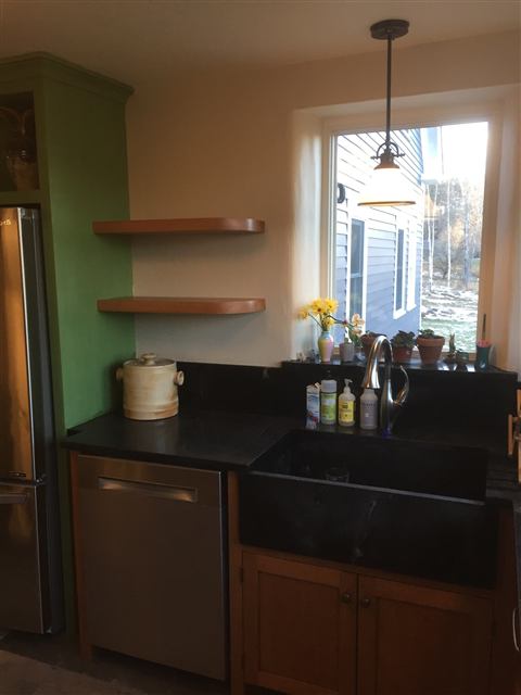 Kitchen corner with a farmhouse sink and open wood shelves