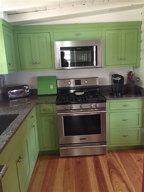 Painted green kitchen cabinets around a gas range