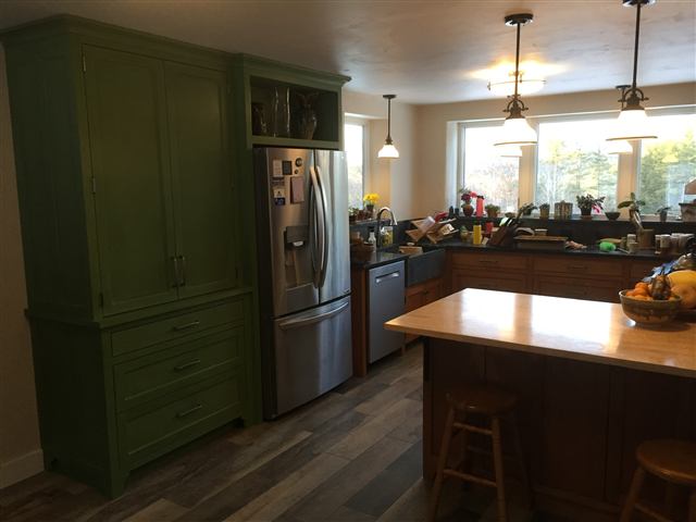 Kitchen with a green tall cabinet and a butcher-block island