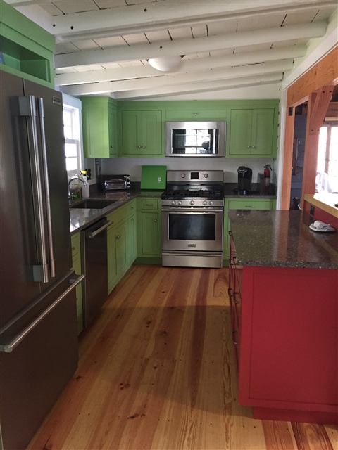 Kitchen with painted green cabinets and a red island