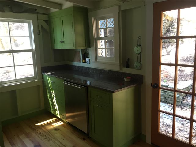 Green kitchen cabinets beside a window and French door