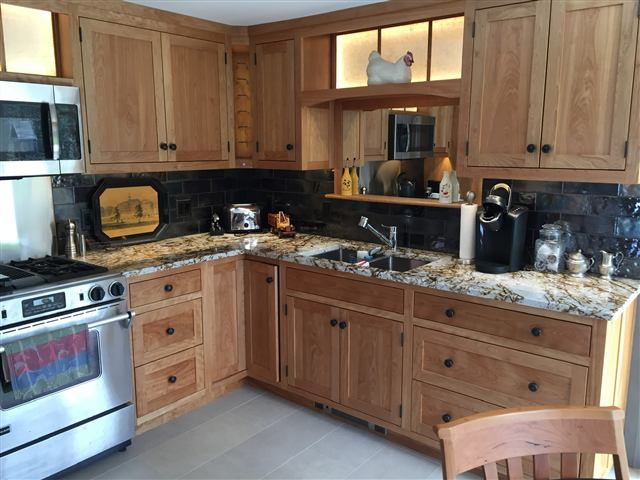Kitchen with custom cabinets, a lit glass transom, and stone counters