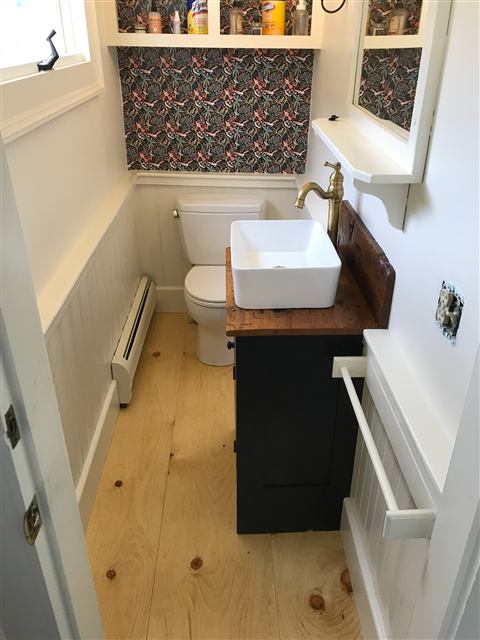 Powder room with wainscot, patterned wallpaper, and a custom vanity