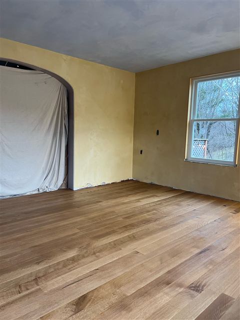 Freshly refinished hardwood floors in an empty room