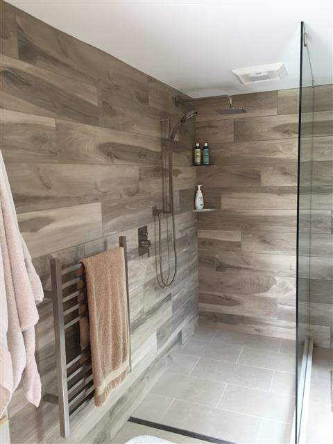 Walk-in shower finished in wood-look porcelain tile with a glass panel
