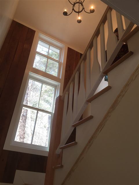 Staircase with a tall window and reclaimed wood wall