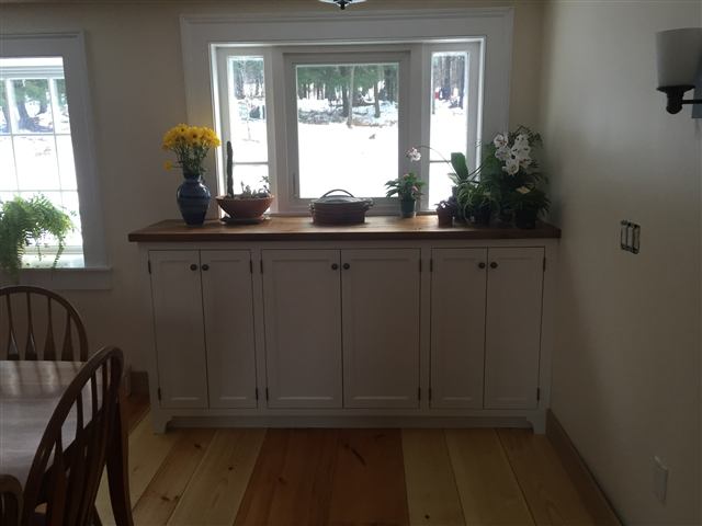 White built-in storage cabinets beneath a window